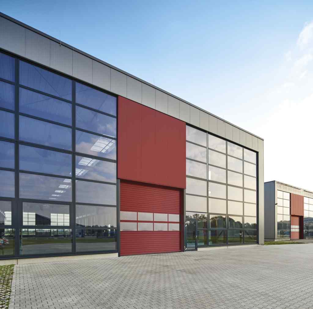 Hörmann ALU-Industrie-Sektionaltor rot an moderner Gewerbehalle mit Glasfassade