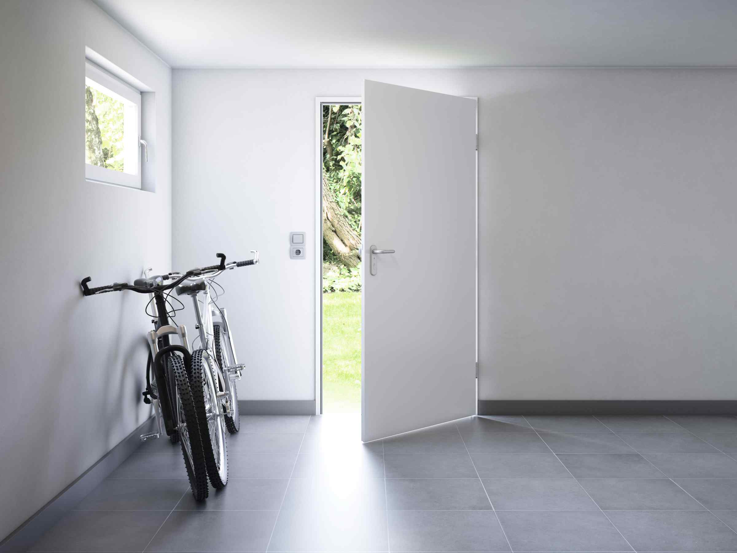 Hörmann Garagennebentür weiß glatt geöffnet — Blick vom Innenraum in den Garten