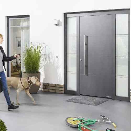 Hörmann Haustür anthrazit mit Streifendekor und zwei Glasseitenteilen — Frau mit Hund beim Eingang