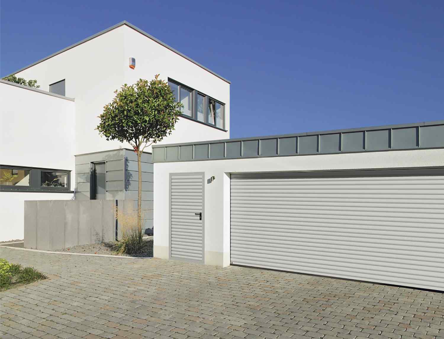 Hörmann RollMatic Garagenrolltor an modernem Wohnhaus — kompakter Aluminium-Kasten über der Öffnung