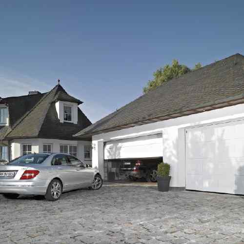 Weißes Einfamilienhaus mit geöffnetem Hörmann Sektionaltor Kassettenprofil — Mercedes in der Einfahrt