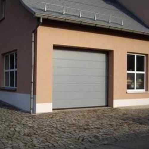 Hörmann Sektionaltor hellgrau mit Sickendesign an Reihenhaus — Pflastersteinvorfahrt