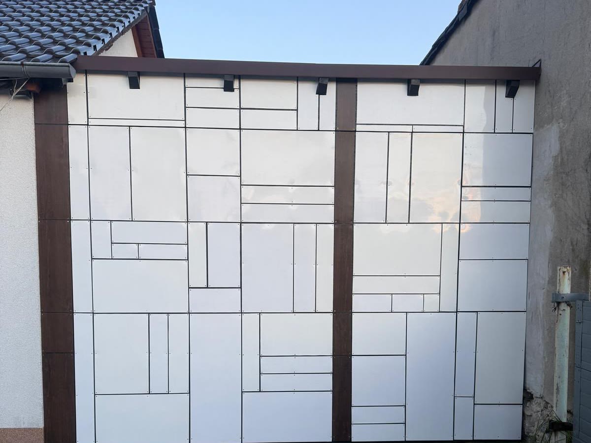 Garagen-Schwingtor mit weißer Plattenverkleidung im Fugenbild der Fassade, geschlossen